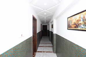 Un pasillo con una escalera, paredes blancas y un cuadro a la derecha.