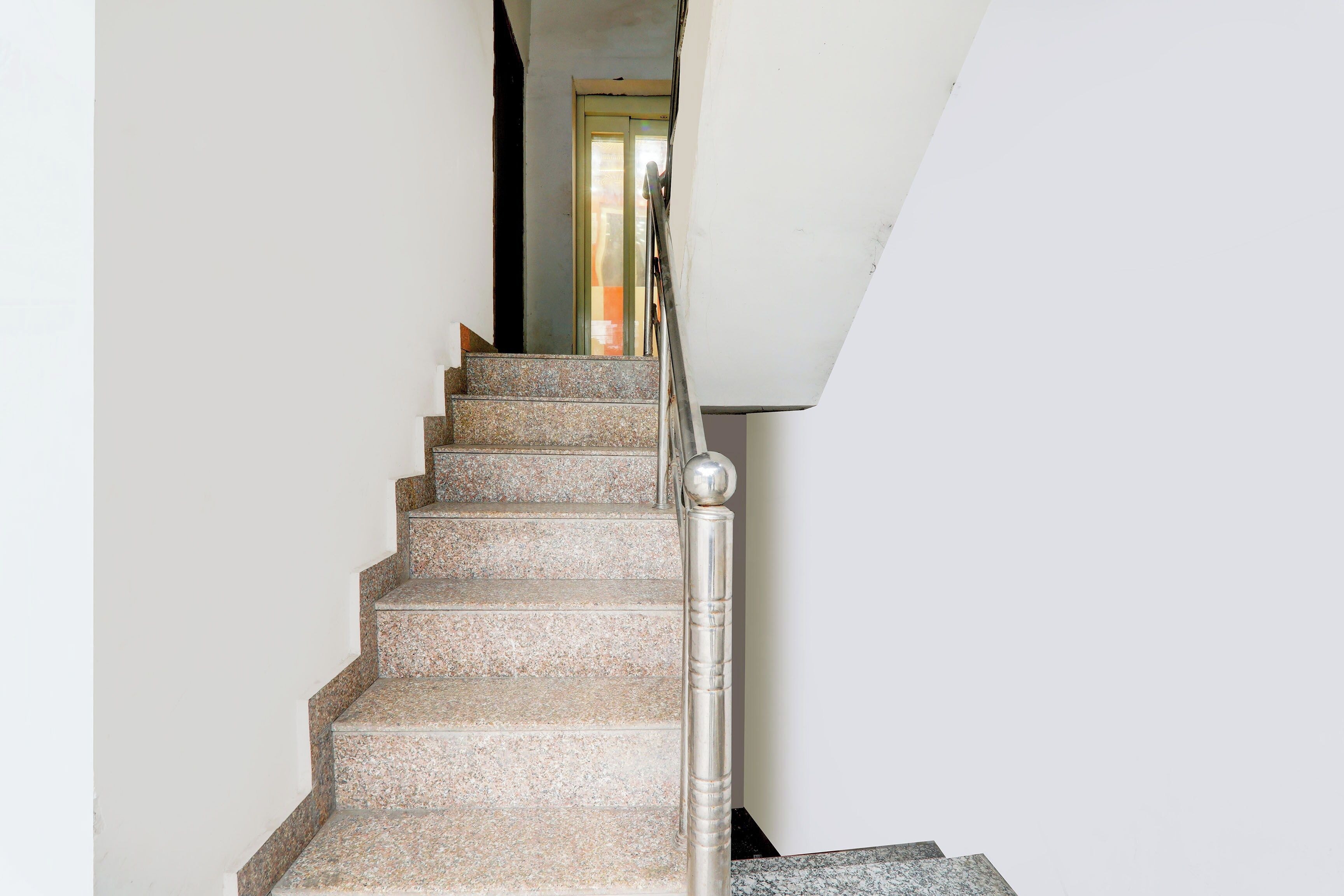 Una escalera con barandilla de metal y una puerta al final.