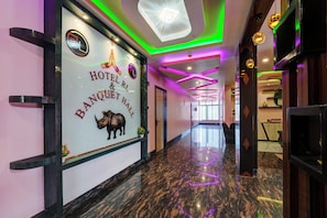 A hotel corridor with a polished marble floor, a reception desk, and a wall with the hotel's name and logo. - HOTEL O RL & BANQUET HALL (Guwahati)