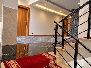 Een modern interieur met een marmeren trap, een houten deur en een gebied met een rode tapijtvloer.