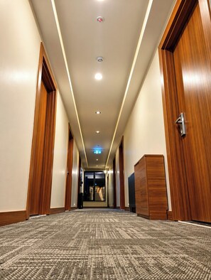 A hotel corridor with wooden doors, a carpeted floor, and recessed lighting. - Perlavista Otel Cafe Restaurant (Elbistan)