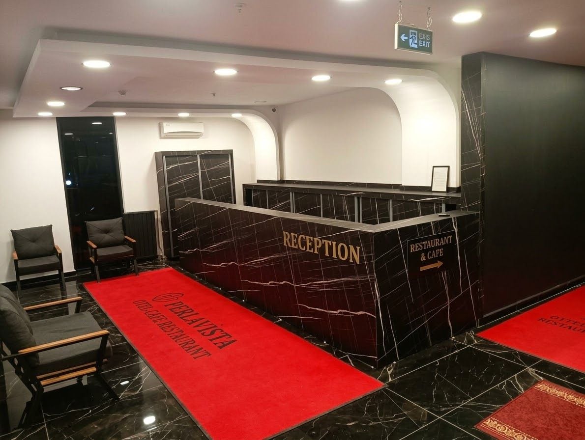 Un'area reception con un bancone in marmo, sedie e tappeti rossi.