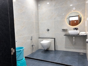 A modern bathroom with a toilet, sink, and shower. - Hotel Shreedha Palace (Indore)