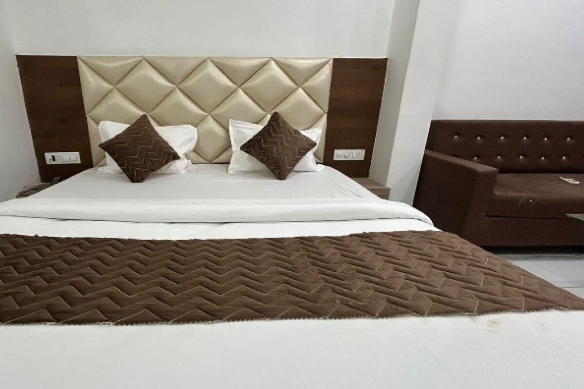 A bed with a quilted headboard, two pillows, and a brown throw blanket.