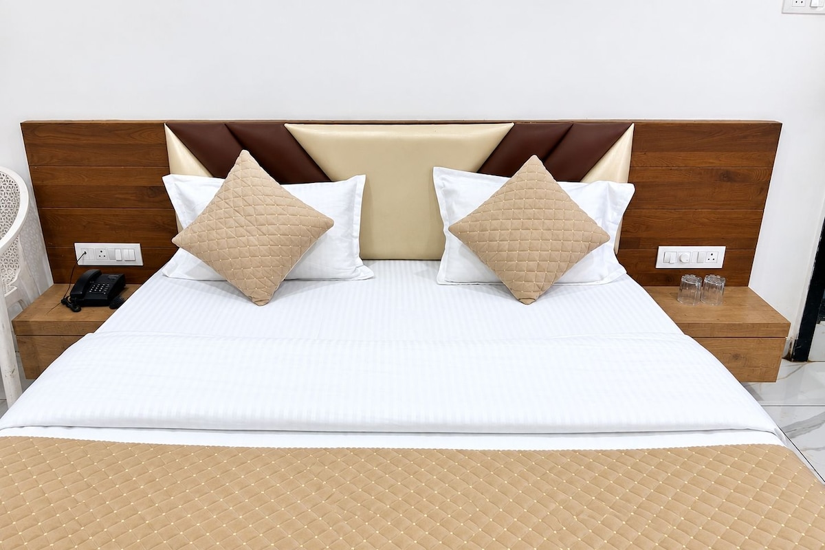 A neatly made bed with a quilted headboard, two bedside tables with a phone and glasses, and a bedside lamp.