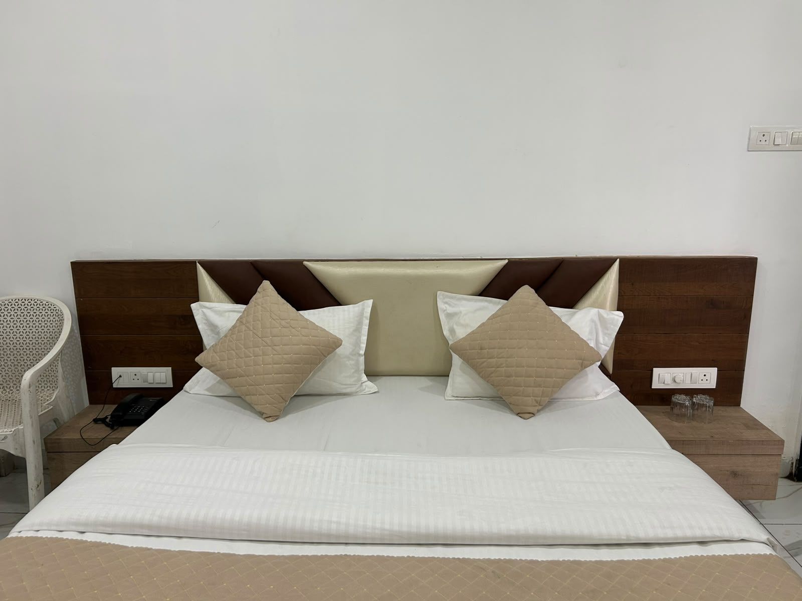 Una cama bien hecha con cabecera, dos almohadas y una manta.