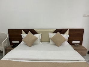 A neatly made bed with a headboard, two pillows, and a blanket. - Hotel Shreedha Palace (Indore)