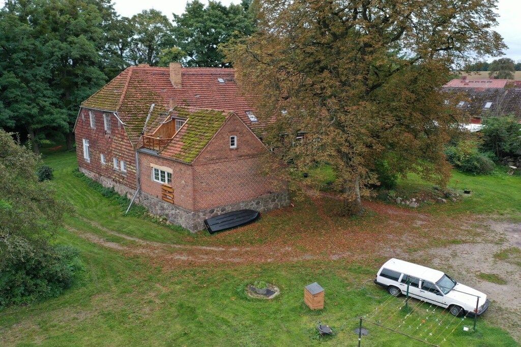 A red brick house with a sloped roof, a small attached garage, and a paved driveway.