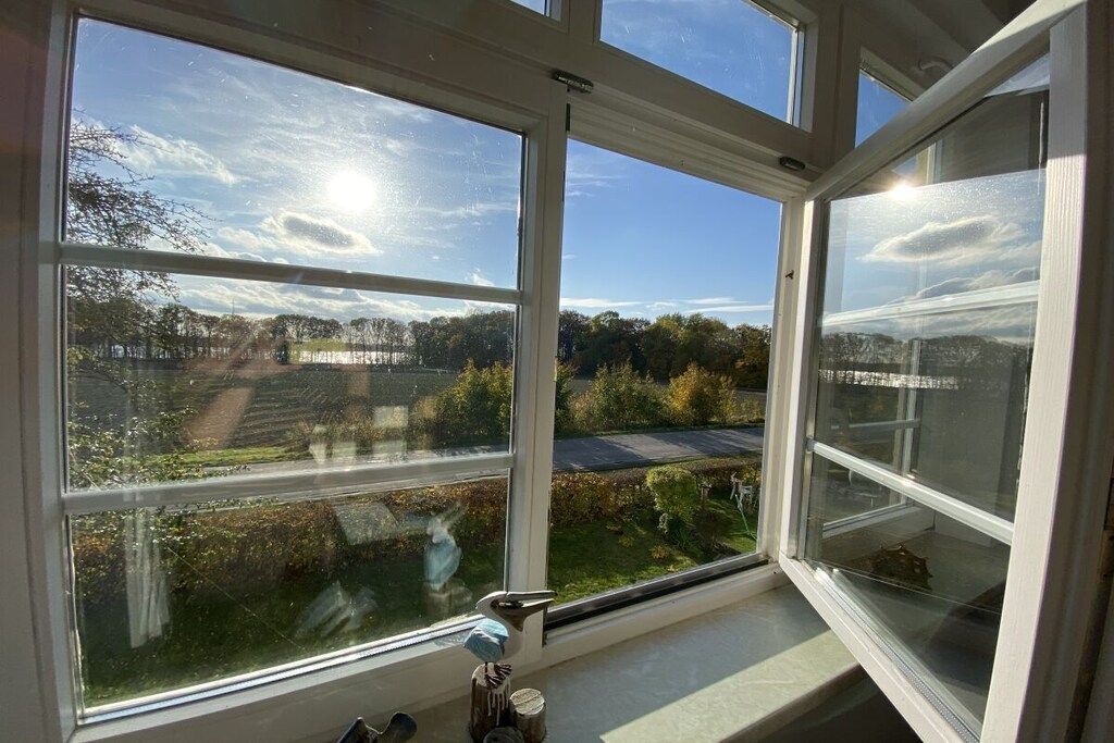 A room with a large window offering a view of a rural landscape.