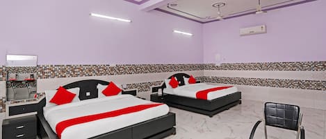 A hotel room with two beds, a chair, a desk, and a ceiling fan.