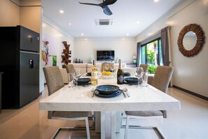 A modern dining area with a white table set for a meal, surrounded by chairs.
