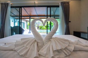 A bed with a towel arranged in the shape of a heart.