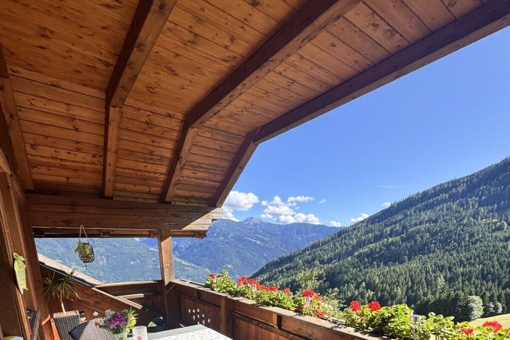 A wooden balcony with a view of a mountain range.