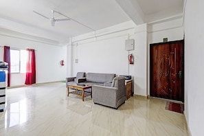 Un salón amplio con un sofá gris, una mesa de centro y un ventilador de techo.