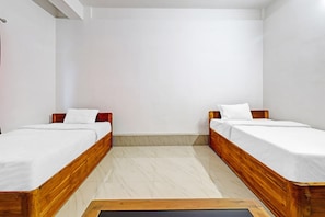A room with two wooden beds, white bedding, and a tiled floor. - Hotel O Assam Inn (Guwahati)