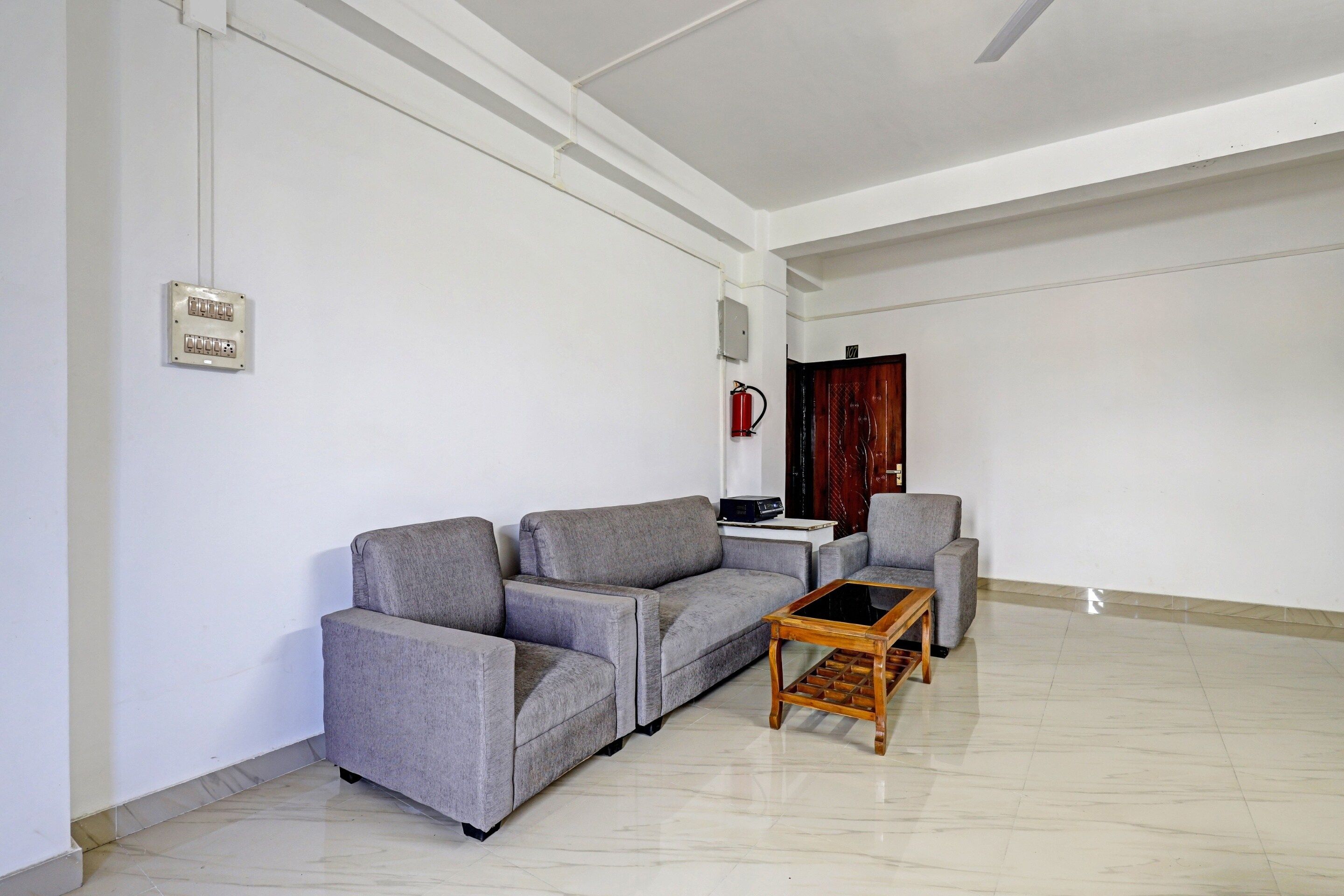 Una sala de estar con un sofá gris, una mesa de centro de madera y una mesita con dispositivos electrónicos.