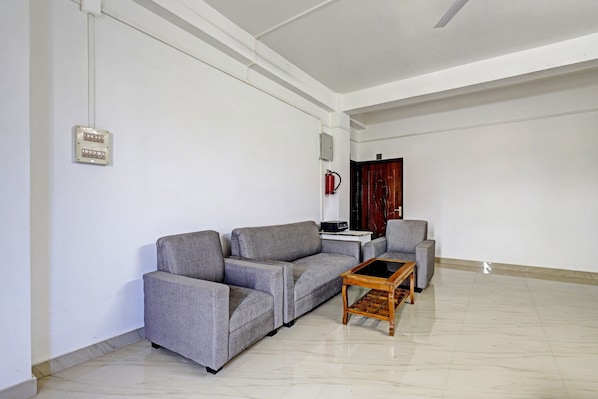 Una sala de estar con un sofá gris, una mesa de centro de madera y una mesita con dispositivos electrónicos.