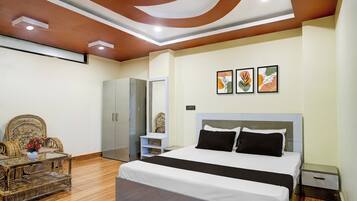 Une chambre à coucher moderne avec un grand lit, une armoire, un coin salon avec une table et des œuvres d’art accrochées au mur.