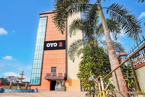 A hotel with a prominent vertical sign, a gated entrance, and a fountain in the foreground. - Hotel O Jyoti Guest House (Guwahati)
