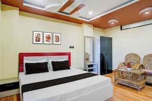 Une chambre d’hôtel comprenant un lit, une armoire, un miroir et une petite table avec des chaises.