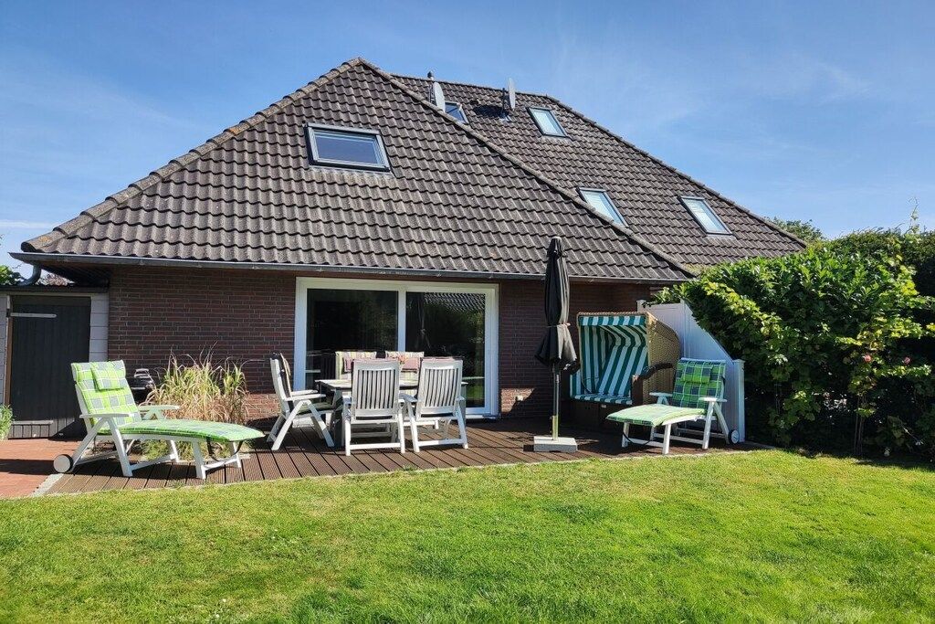 A house with a sloped roof, a patio with outdoor furniture, and a grassy yard.