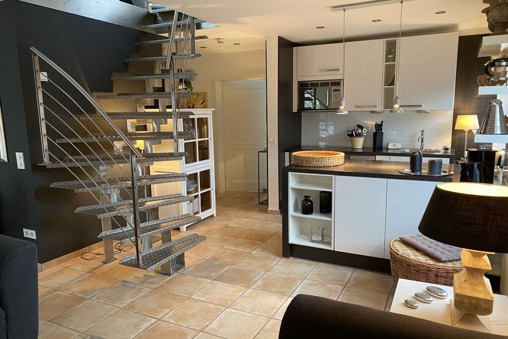 A modern kitchen with white cabinets, a built-in stove, and a dining area with a table and chairs.