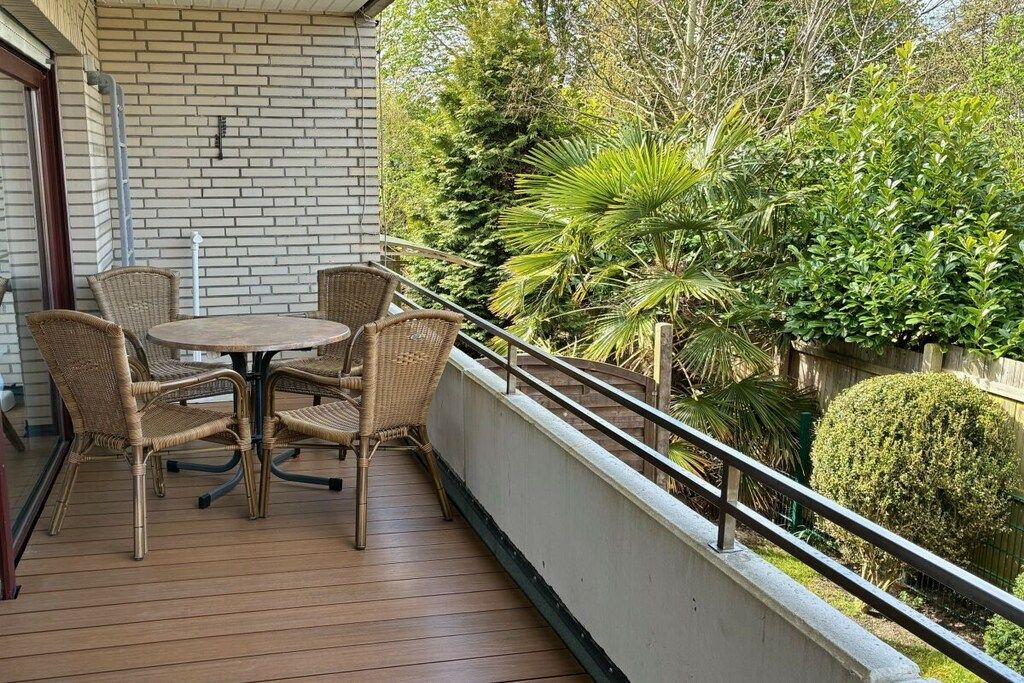 Un balcon doté de meubles en osier et offrant une vue sur un jardin.