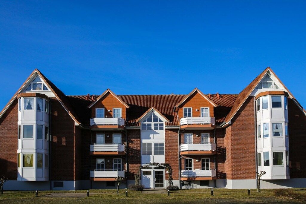 A multi-story residential building with a symmetrical facade, multiple balconies, and a central entrance.