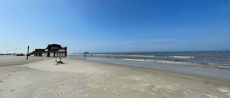 A beach with a lifeguard tower and a building in the background.