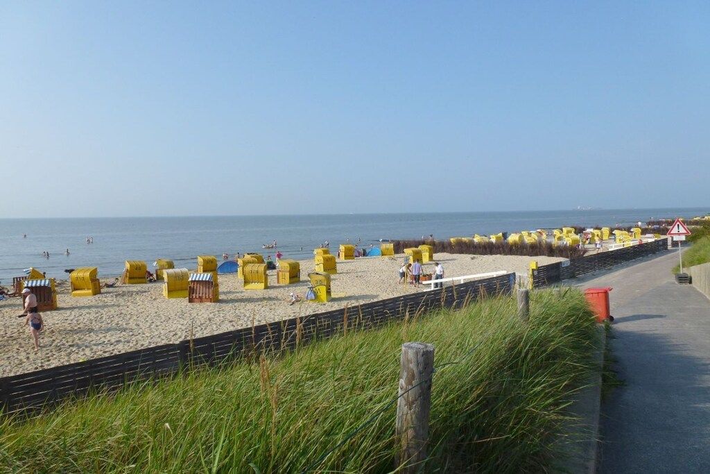 Une plage avec des cabanes de plage jaunes et une promenade dallée.