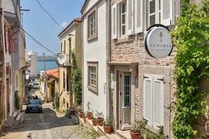 Une rue étroite bordée d’immeubles, une enseigne indiquant « Lunaria Guest House », et une voiture garée le long de la rue.
