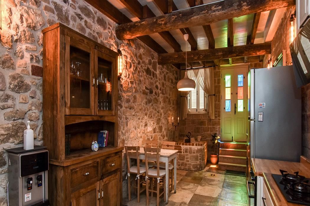 Una cocina rústica con paredes de piedra, armarios de madera, una mesa de comedor y un refrigerador.