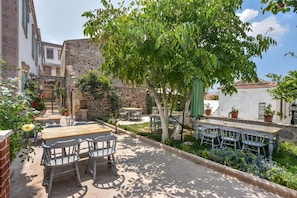 Un espace extérieur aménagé avec des tables et des chaises, entouré de verdure et de murs en pierre.