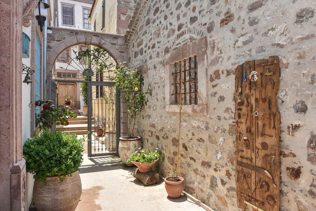 Un estrecho callejón con paredes de piedra, una puerta de madera y plantas en macetas.