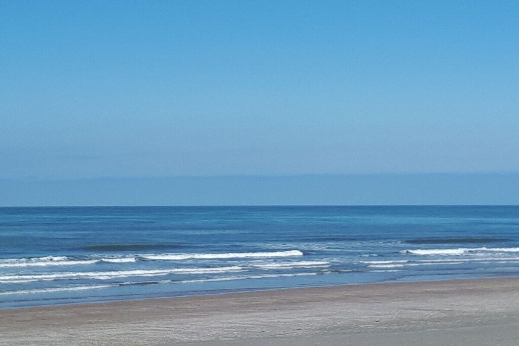 Een strand met golven en een heldere lucht.