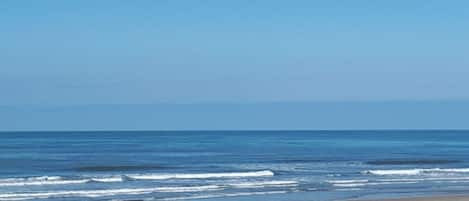 A beach with waves and a clear sky.