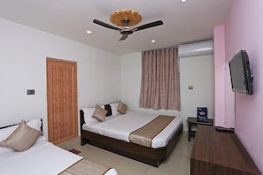 Ein Hotelzimmer mit einem Bett, einem Schreibtisch, einem Fernseher und einem Deckenventilator.