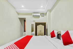 A hotel room with a bed, a wardrobe, an air conditioning unit, and a door. - Hotel O Govind Guest House (Gorakhpur)