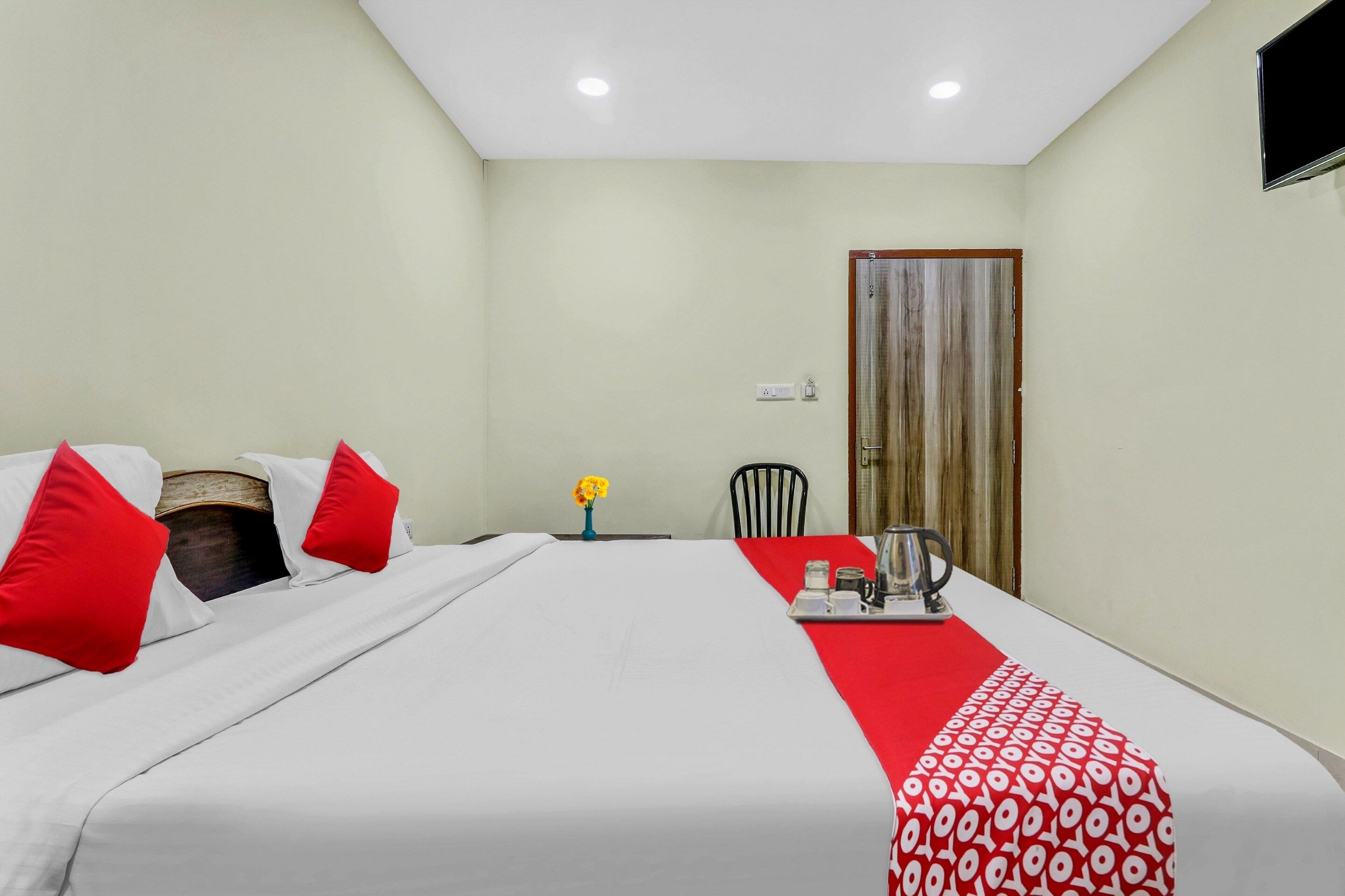 Una habitación de hotel con cama, una mesa con bandeja, una silla y una puerta.