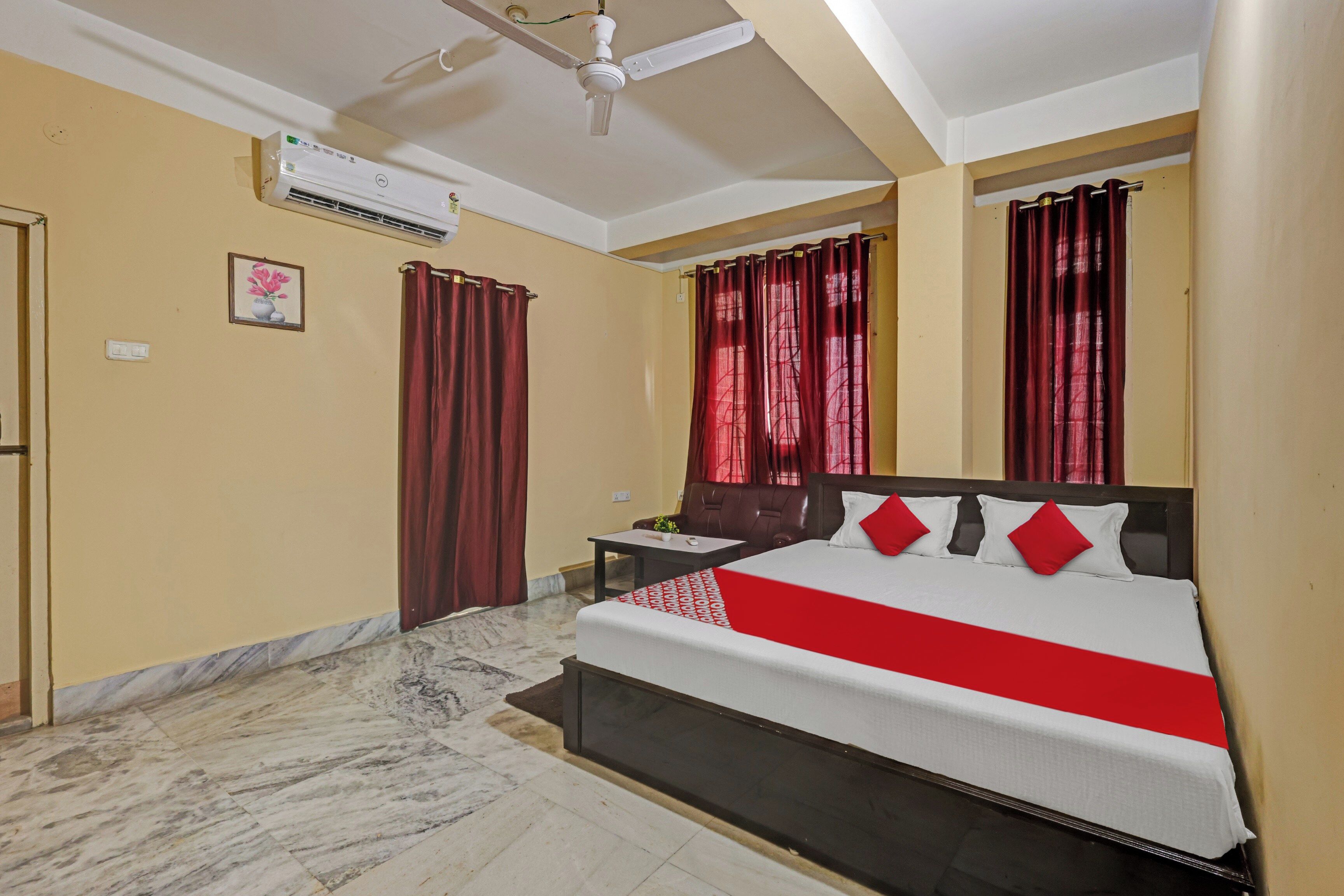 Habitación de hotel con cama, escritorio, silla, mesita de noche, aire acondicionado y ventana con cortinas.