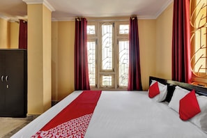 Ein Hotelzimmer mit einem Bett, einem Kleiderschrank und einem fenster mit Vorhängen.