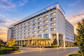 Un hotel moderno con fachada de vidrio, varios pisos y entrada cubierta.