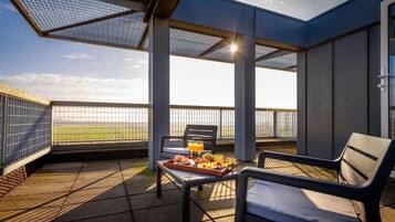 Un balcon avec une table préparée pour le petit-déjeuner, une chaise et une vue sur le ciel.