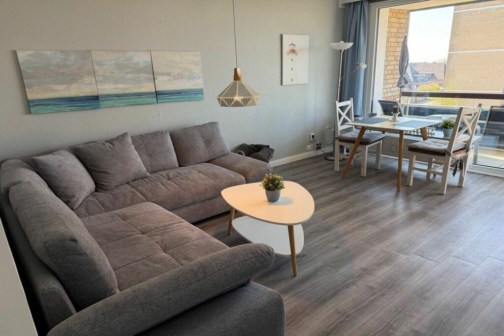 Un salon moderne avec un canapé d’angle, une table basse ronde et un coin repas comprenant une table et des chaises.