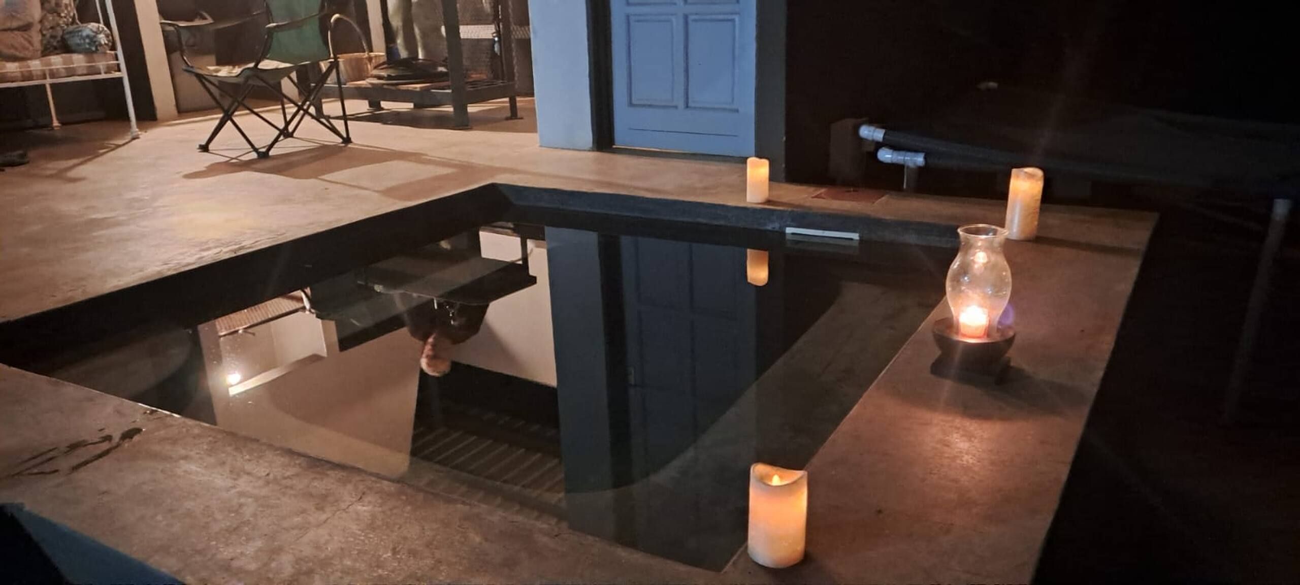 Een moderne badkamer met een douche met glazen wand, een wastafel en twee brandende kaarsen op het aanrecht.