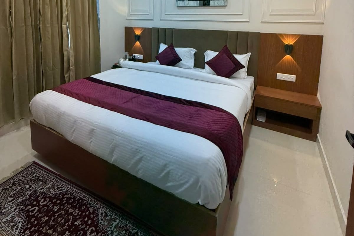 A bedroom with a bed, a ceiling fan, a nightstand, a rug, and a wall-mounted light fixture.
