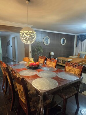 A dining area with a wooden table, chairs, and a decorative hanging light fixture. - “Your Peaceful Getaway Among the Hills” (Wallan)