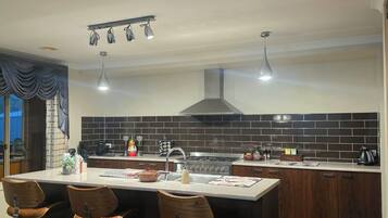 A modern kitchen with a central island, bar stools, a stove, and a large window.