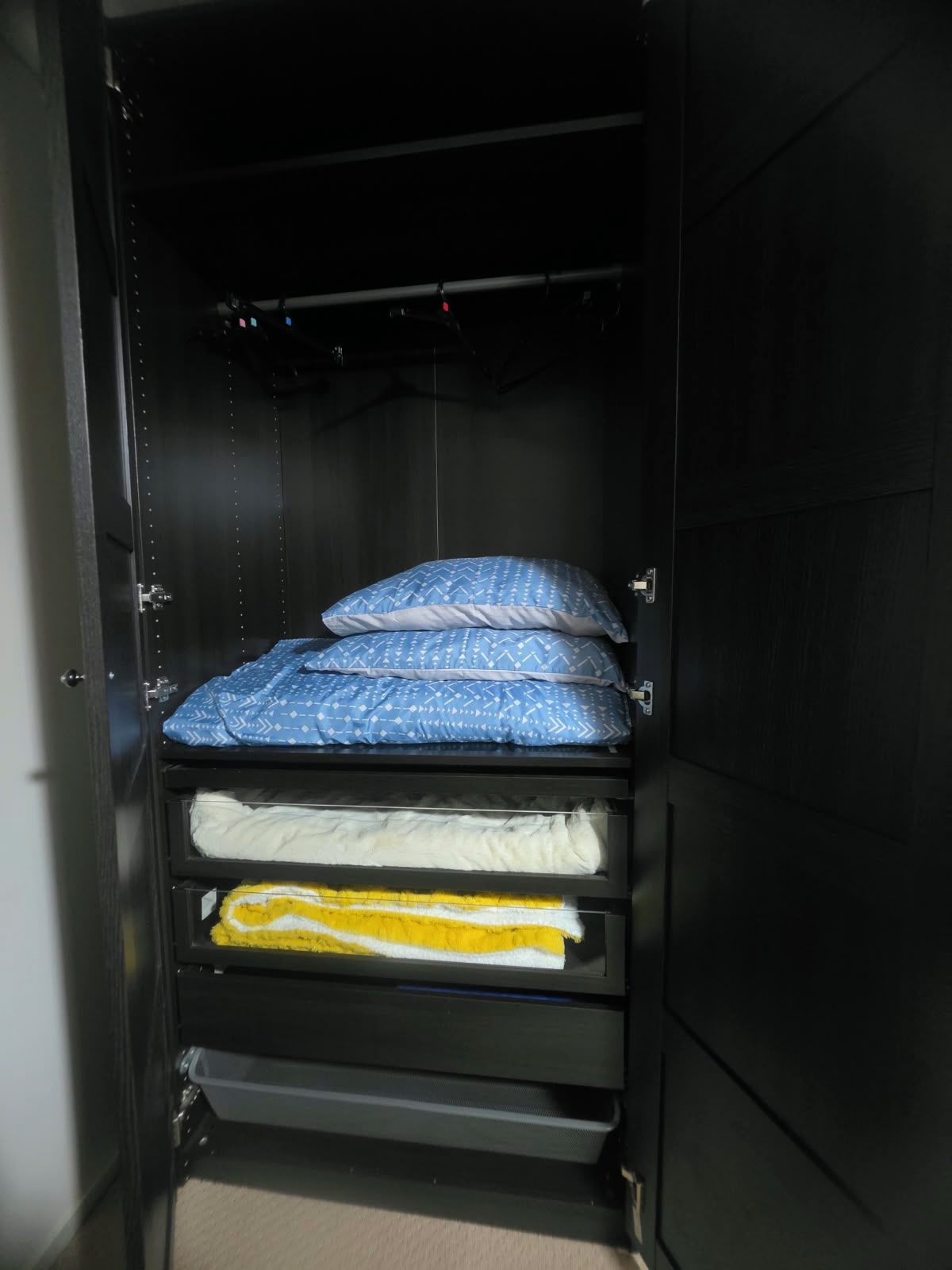 A bunk bed with a blue patterned mattress and pillows, a white mattress below, and a yellow blanket at the bottom.