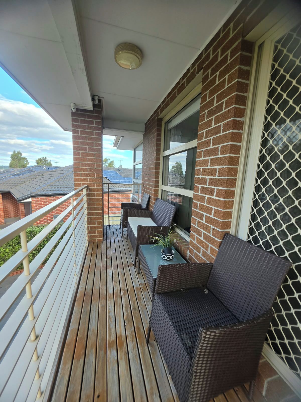 A balcony with wicker furniture, a small table, and a potted plant.